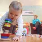 Photo by Kelly Sullivan/ Peninsula Clarion Nora Arness plays with toys while her mother Julie Arness chats with Kara Abel Thursday, Nov. 12, 2015, at Katy Bethune's home in Nikiski, Alaska.