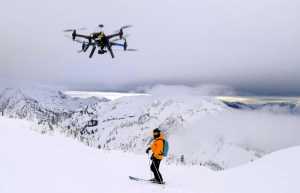 This Dec. 2014 photo shows a drone hovering by a skier as he makes his way down mountainside at resort at Revelstoke, B.C., Canada. Some US ski resorts are exploring the possibility of "drone zones" where professionally operated drones can produce customized video that show off individuals skiers in action. (Jason Soll/Cape Productions via AP)