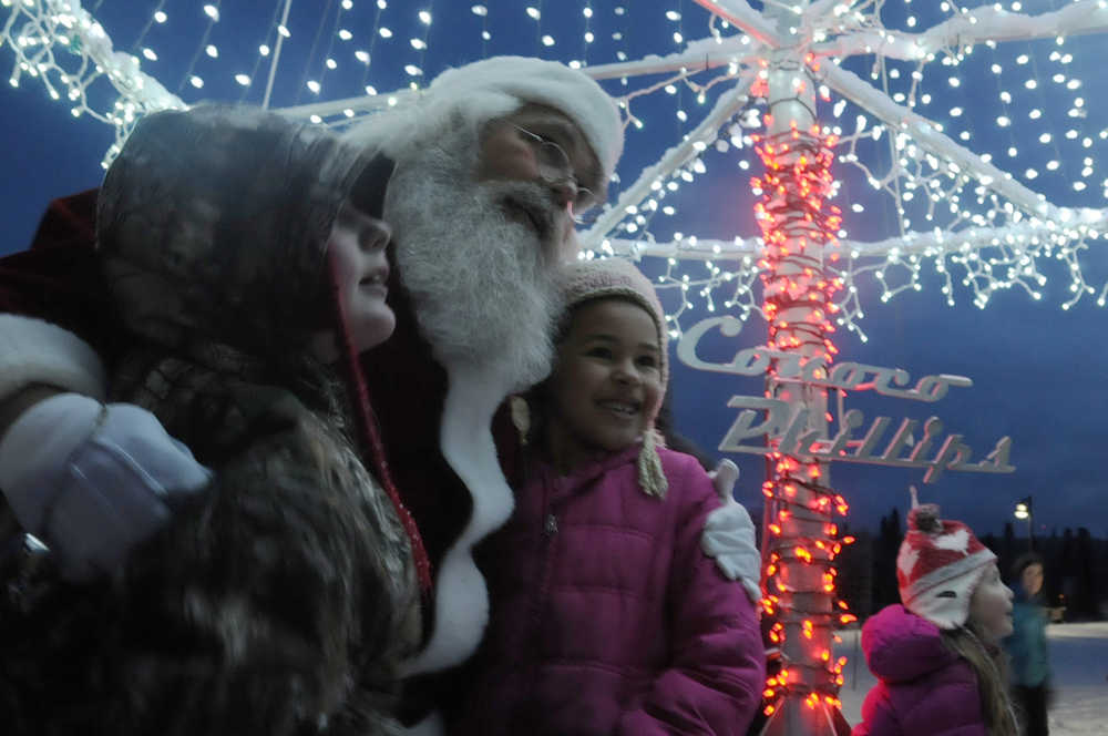 Ben Boettger/Peninsula Clarion Children pose with David Caswell (as Santa Claus) under the Conoco Philips-sponsored Soldotna christmas tree lights on Saturday, Dec. 5 in Soldotna Creek Park.