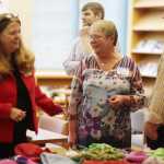 Photo by Kelly Sullivan/ Peninsula Clarion Nikiski Senior Center Director Jill Smith, school nurse and club organizer Glynes Gerrior chat beside Principal Dan Carstens Thursday, Dec. 10, 2015, in the school's library in Nikiski, Alaska.