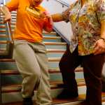 Ben Boettger/Peninsula Clarion Nicole Harmon (left) descends a staircase with the help of physical therapist assistant Sabrina Royster on Thursday, Dec. 10 at the Denai'ina Wellness Center in Kenai.