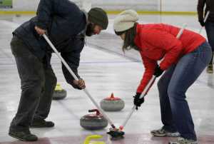 In this Jan. 2 photo, Rich Savoyski, left, and Kara Zwickey furiously sweep in front of their teams' curling stone to bring it into the red-outlined house to score a goal at Kevin Bell Arena in Homer.(Anna Frost/The Homer News)