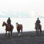Photo by Megan Pacer/Peninsula Clarion Sterling resident Sierra Craven, left, and Kenai resident Mercedes Tapley, right, gather with the rest of a group of Alaska C & C Horse Adventures riders on Monday, Jan. 18, 2016 on the beach of the Kenai River in Kenai, Alaska. The group members participate in year-round riding, said the group's owner, Connie Green.