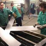 Ben Boettger/Peninsula Clarion Kenai Central High School freshmen Jude Gabriel (left) and Damien Redder lift the fresh-cut "K" - part of the Kenai sign the two are making - from a plasma cutter table  on Wednesday, Feb. 3 at Kenai Central High School.