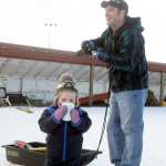 Photo by Megan Pacer/Peninsula Clarion Soldotna resident Jason Sulley and his son, 2-year-old Corbin, look on as Jason's wofe, Angie, collects a prize during the Women's Stud Run on Sunday, Feb. 7, 2016 at the Tsalteshi Trails in Soldotna, Alaska. Formerly the Ski for Women, the Stud Run allowed participants to ski, run or snowshoe the 5K trail.