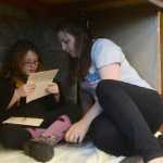 Photo by Megan Pacer/Peninsula Clarion Mariah Ross and her 6-year-old daughter, Adelynn, read tucked away in a makeshift "cupboard under the stairs" during Harry Potter Book Night on Thursday, Feb. 4, 2016 at the Soldotna Public Library in Soldotna, Alaska.