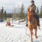 Photo by Megan Pacer/Peninsula Clarion Connie Green and her horse, Sequoia, pull 11-year-old Mercedes Tapley and 8-year-old Sophie Tapley around an enclosure on a sled on Monday, Feb. 8, 2016 at Alaska C&C Horse Adventures In Soldotna, Alaska.