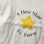 Photo by Kelly Sullivan/ Peninsula Clarion Nikiski North Star Elementary School teacher Gina Ellis designed the onsies that go to the school's growing families Wednesday, Feb. 24, 2016, at the school in Nikiski, Alaska.