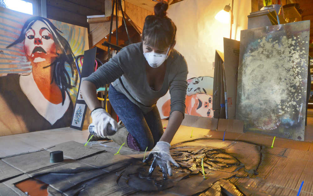 Spraypaint artist Gemma Amorelli sprays in the black outline of a one-color stencil of a friend's face on Monday, Feb. 22 near Soldotna. "I like people with a lot of wrinkles and character in their face," Amorelli said. "I picked this one because it's a picture of somebody I know with his face kind of crinkled up in the middle, like he's smelling something gross."   Amorelli