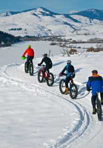 ADVANCE FOR WEEKEND EDITIONS, JAN. 16-17- In this photo taken Jan. 1, 2015, Washington State Park volunteer Dave Acheson leads a group of fat tire bike riders along Rex Derr Trail overlooking Pearrygin Lake near Winthrop, Wash. (Stephen Mitchell via AP)