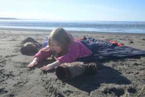 Isla Nelson, 5, plays in the sand while her mother, Soldotna resident Betty Nelson, and grandmother, Juneau resident Sue Carlson, enjoy a sunny day at the beach on Sunday, March 13, 2016 at the mouth of the Kenai River in Kenai, Alaska.
