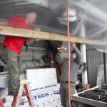 Photo by Kelly Sullivan/ Peninsula Clarion Harry Ala and Jim Hansen work on installing plastic covers below the upper level of his family's greenhouse so the plants above don't drip debri onto the plants below Wednesday, March 9, 2016, at Ridgeway Farms in Soldotna, Alaska.