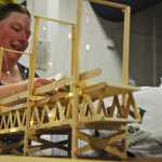 Photo by Elizabeth Earl/Peninsula Clarion Holly West, a senior at Kenai Peninsula College, works on her project at the college's 3D design studio on Friday, April 15, 2016. West said her project, building the Bay Bridge from popsicle sticks, is part of a project conveying the connection her uncle had traveling back and forth from China for work.
