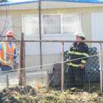 Members of the Kenai Fire Department and Enstar Natural Gas Co. finish putting out a shed fire Thursday, April 21, 2016 on North Dogwood Road in Kenai. The fire, which took about a half hour to extinguish, burnt two sheds, a chicken coop and the outside of a home, but harmed no one.