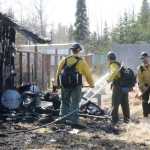 Members of the Alaska Division of Forestry finish putting out a fire that consumed two sheds and a chicken coop Thursday, April 21, 2016 on North Dogwood Road in Kenai. The fire, which took about a half hour to extinguish, also burnt the outside of a home, but harmed no one.