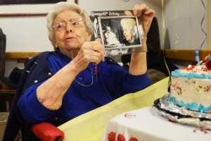 Photo by Megan Pacer/Peninsula Clarion Hazel George opens a present - side-by-side photos of her as a baby and in the present - during a birthday party Sunday, April 24, 2016 at Heritage Place in Soldotna, Alaska. George joined the other centenarians in the state when she turned 100 Sunday.