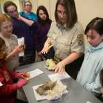 Girl Scouts examine a pair of skulls - one a wolf, the other a mystery - with Kenai National Wildlife Refuge Park Ranger Leah Eskelin during the Women of Science event on Saturday, April 30 at Kenai Peninsula College.