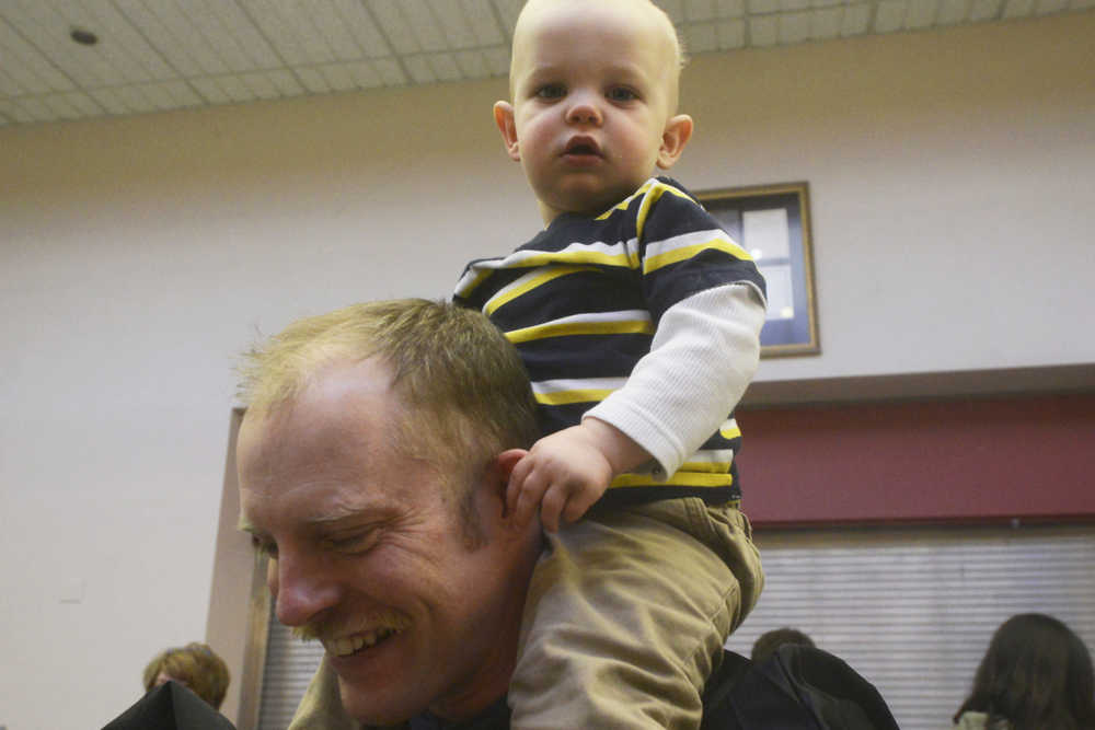 Photo by Megan Pacer/Peninsula Clarion Darren Finley carries his son, 15-month-old Maximus, after his graduation ceremony Thursday, May 5, 2016 in the Renee C. Henderson Auditorium at Kenai Central High School in Kenai, Alaska. Finley graduated Kenai Peninsula College's paramedic technology program and has been employed with Central Emergency Services since November 2015.