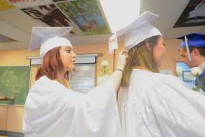 Photo by Megan Pacer/Peninsula Clarion Richele McGahan adjusts the pins in Victoria Cizek's hair moments before they joined their two fellow senior classmates to walk into their graduation ceremony Sunday, May 8, 2016 at Cook Inlet Academy in Soldotna, Alaska. The school had a smaller graduating class than usual, with only four high school seniors.