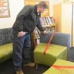 Photo by Megan Pacer/Peninsula Clarion Kenai Vice Mayor Brian Gabriel inspects a vandalized piece of furniture Wednesday, May 25, 2016 at the Kenai Community Library in Kenai, Alaska. Several chairs and a stool were destroyed with a paint-like substance, and a couch was slashed with a knife at the library last week.