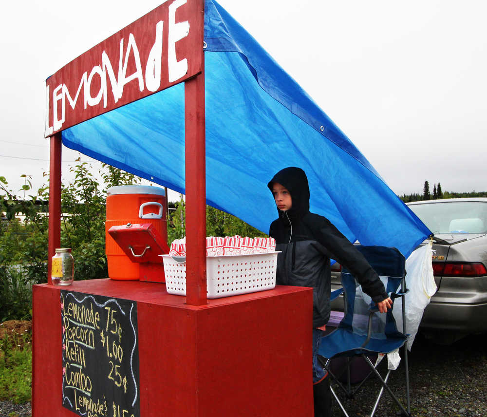 Paxton McKnight sets up his lemonade and popcorn stand near the Sushi Exchange restaurant on Saturday, June 11 in Soldotna. McKnight was one of several local children who participated in Lemonade Day, an event created by the Kenai Chamber of Commerce to promote business skills among youth.