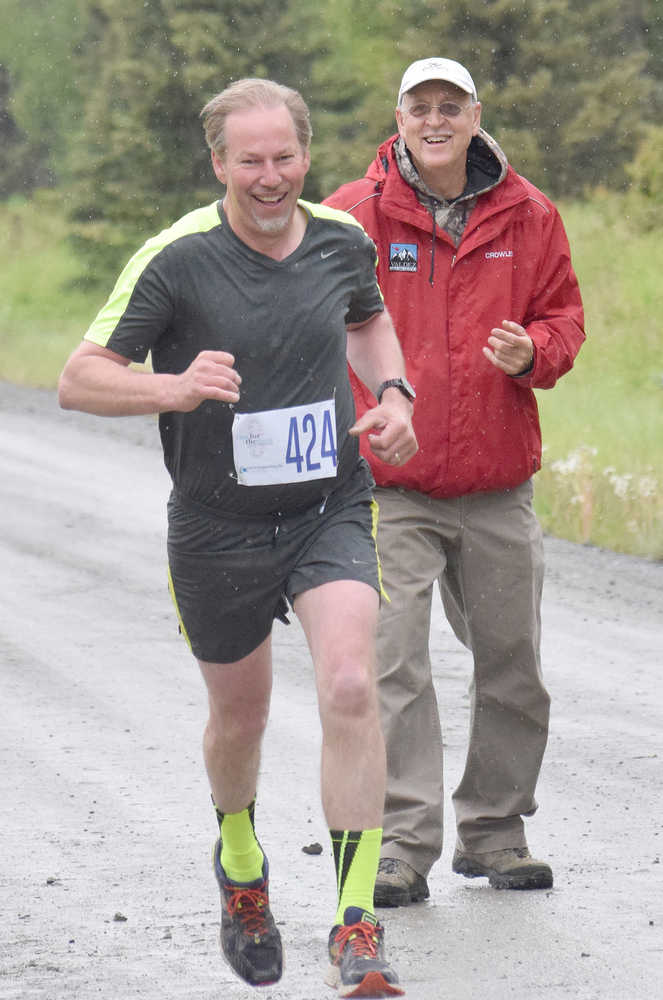 Photo by Joey Klecka/Peninsula Clarion Soldotna runner Carl Kincaid (424) receives encouragement from a course worker in Saturday's men's 5K Run for the River race in Soldotna.