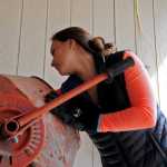Photo by Elizabeth Earl/Peninsula Clarion Jenna Hansen reaches into the cement mixer she uses to break up glass at her home in Nikiski, Alaska on Wednesday, June 1, 2016. Hansen and her family turn recycled glass into jewelry to sell.