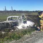 Photo by Megan Pacer/Peninsula Clarion Firefighters finish up work on a vehicle that rolled over and caught fire Wednesday, June 15, 2016 on Marathon Road between Nikiski and Kenai. The burning vehicle caught a small area of grass of fire, which was also put out.