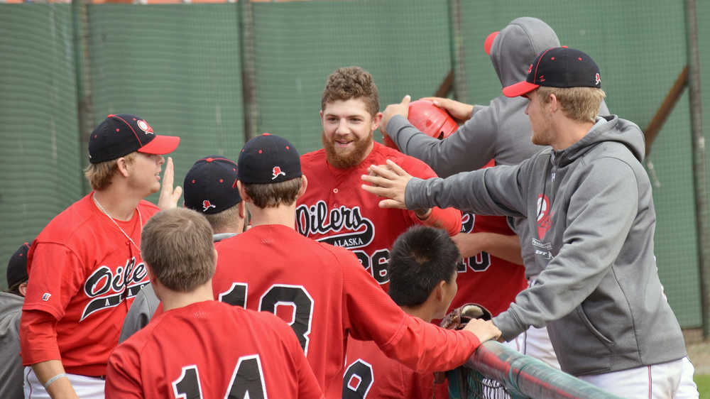 Photo by Jeff Helminiak/Peninsula Clarion Oilers Alex Seifert (26) and Ryan Smith (10) accept congratulations after scoring in the sixth inning to give the Oilers a 4-2 lead against the Chugiak Chinooks on Sunday at Coral Seymour Memorial Park in Kenai.