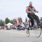 Photo by Kelly Sullivan/ Peninsula Clarion Doug Field hopped on and off his Penny Farthing during Kenai's July 4th Parade to demonstrate how to ride the tall bicycle Monday, July 4, 2016 in Kenai, Alaska.