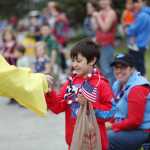 Photo by Kelly Sullivan/ Peninsula Clarion Samuel Strouss happily takes a mini rubber duck from a Kenai Elk's Club volunteer during Kenai's July 4th Parade on Monday, July 4, 2016 in Kenai, Alaska.
