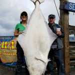Photo courtesy Seward Chamber of Commerce "Captain T" of Crackerjack Sportfishing Charters poses with the 193.6-pound halibut her client, Jason Grieg of Ferndale, Wash., caught on June 30, 2016 out of Seward, Alaska. "Captain T" made history for being the first female captain to host the winner of the Seward Halibut Tournament.