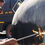 Ben Boettger/Peinsula Clarion RAW welder Laron Hagan burns paint off a buoy, preparing to plasma-cut the steel surface with a scene of dragons and skeletons on Monday, July 18 at the RAW Welding workshop outside Soldotna.