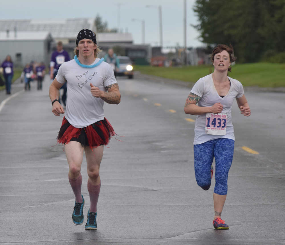 Photo by Joey Klecka/Peninsula Clarion Kyle McNally of Colorado (left) sprints to the finish line with Nikki Dixon in Saturday's Run for Women 10K race. McNally ran with Dixon in the race with the condition that he "dress" up for the event.
