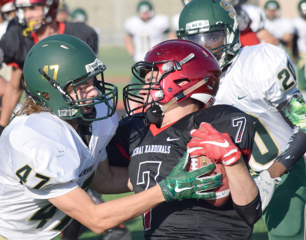 Photo by Jeff Helminiak/Peninsula Clarion Service's Jalen Dunlap tries unsuccessfully to pry the ball from Kenai Central's Avery Heiber on a kickoff return Friday at Ed Hollier Field in Kenai.