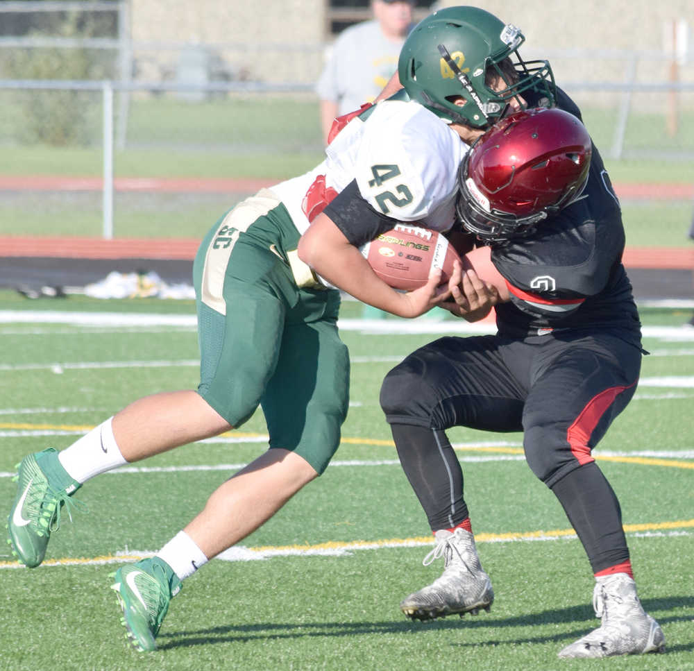Photo by Jeff Helminiak/Peninsula Clarion Kenai Central's Nick Beeson wraps up Service's Conner O'Farrell for a loss Friday at Ed Hollier Field in Kenai.