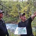Ben Boettger/Peninsula Clarion Standing near the prospective site of the Grant Lake Hyrdoelectric project's generating station, fishery biologist John Stevenson listens to Fuel Supply Manager Mike Salzetti outline plans for a powerhouse, detention pond, and water tunnel outlet on the hillside about Grant Creek on Wednesday, Sept. 7 near Moose Pass.  Stevenson, an employee of biological consulting company BioAnalysts, studied fish in Grant Creek as part of the licensing process for the Grant Lake project.