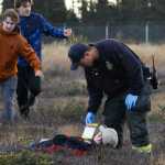 Photo by Megan Pacer/Peninsula Clarion Kenai River Brown Bears hockey player Bailey Seagraves poses as a dead plane crash victim and waits to be rescued during a mass casualty drill Tuesday, Oct. 11, 2016 at the Kenai Municipal Airport in Kenai, Alaska. The airport is required by the Federal Aviation Administration to hold the drill every three years to test its emergency planning.