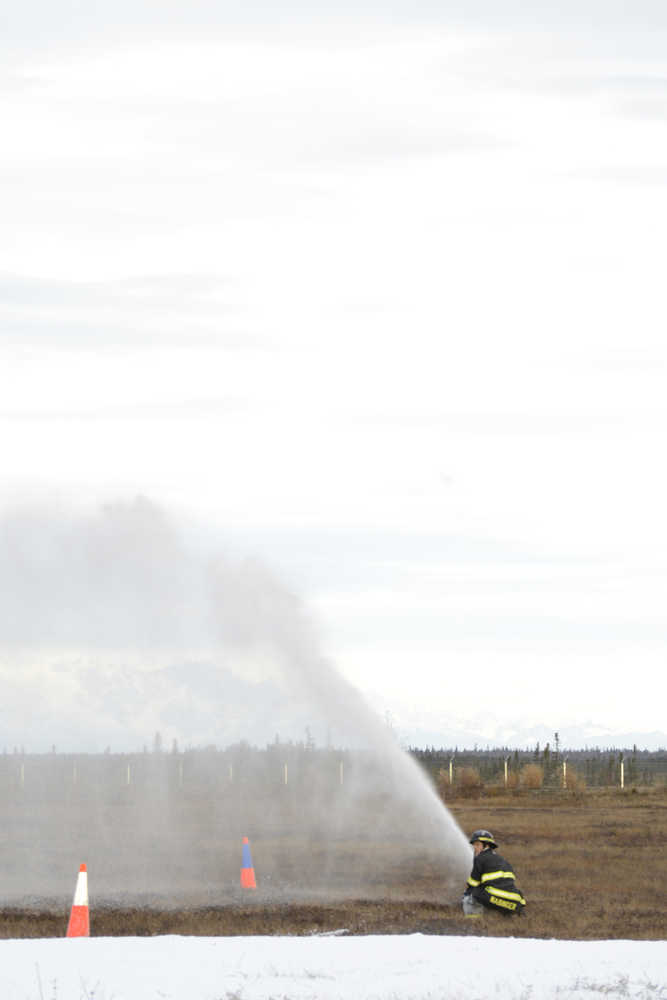 Photo by Megan Pacer/Peninsula Clarion Kenai Fire Battalion Chief Tony Prior and a firefighter help volunteer Sloan Young, who is visiting Alaska from Orlando, Florida, onto a stretcher during a mass casualty drill Tuesday, Oct. 11, 2016 at the Kenai Municipal Airport in Kenai, Alaska. Young joined more than 30 volunteers who posed as crash victims during the drill which the airport is required by the Federal Aviation Administration to hold every three years to test its emergency planning.