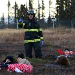Photo by Megan Pacer/Peninsula Clarion A firefighter communicates with other emergency responders while volunteers wait to be rescued during a mass casualty drill Tuesday, Oct. 11, 2016 at the Kenai Municipal Airport in Kenai, Alaska. More than 30 volunteers turned out to act as plane crash victims and medics at the drill the airport is required by the Federal Aviation Administration to hold every three years to test its emergency planning.