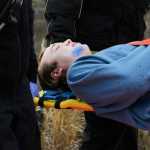 Photo by Megan Pacer/Peninsula Clarion Kenai River Brown Bears hockey player Alex Dingeldein feigns injury while being carried on a stretcher during a mass casualty drill Tuesday, Oct. 11, 2016 at the Kenai Municipal Airport in Kenai, Alaska. He and more than 30 others volunteered to act as plane crash victims and medics during the drill the airport is required by the Federal Aviation Administration to hold every three years to test its emergency planning.