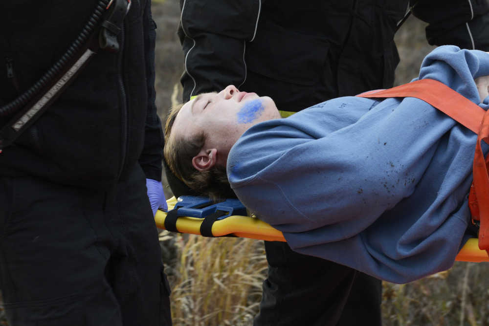 Photo by Megan Pacer/Peninsula Clarion Kenai River Brown Bears hockey player Alex Dingeldein feigns injury while being carried on a stretcher during a mass casualty drill Tuesday, Oct. 11, 2016 at the Kenai Municipal Airport in Kenai, Alaska. He and more than 30 others volunteered to act as plane crash victims and medics during the drill the airport is required by the Federal Aviation Administration to hold every three years to test its emergency planning.