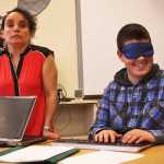 Photo by Ben Boettger/Peninsula Clarion Kenai Peninsula Borough School District teacher for the visually-impaired Jordana Engebretson (left) helps blindfolded student Steven Smith type a message on her computer, which has a text-to-speech program that reads back the letters and words Smith types, during RIver City Academy's Blindness Challenge on Thursday, Oct. 13 in Soldotna.