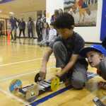 Photo by Megan Pacer/Peninsula Clarion Kalifornski Beach Elementary fifth grader Avery Ciufo, 10, signs her name after her team, the Caribou Creators, let their mouse trap vehicle loose in competition, while teammate Nicholas Rackley, 11, and Elizabeth Morris, a judge, look on during the annual Mind A-Mazes competition at Soldotna Prep in Soldotna, Alaska. The 44 teams that registered from across the school district this year had about six weeks to design and build their devices for the event facilitated by the district's Quest Program.