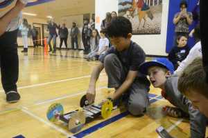 Photo by Megan Pacer/Peninsula Clarion Kalifornski Beach Elementary fifth grader Avery Ciufo, 10, signs her name after her team, the Caribou Creators, let their mouse trap vehicle loose in competition, while teammate Nicholas Rackley, 11, and Elizabeth Morris, a judge, look on during the annual Mind A-Mazes competition at Soldotna Prep in Soldotna, Alaska. The 44 teams that registered from across the school district this year had about six weeks to design and build their devices for the event facilitated by the district's Quest Program.