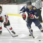 Photo by Joey Klecka/Peninsula Clarion Homer forward Dimitry Kuzmin (12) carries the puck up the ice with Kenai Central defenseman Alyssa Stanton in tow Thursday evening at the Soldotna Regional Sports Complex.