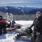 In this Tuesday, March 17, 2016 photo, Bob Seelye and Mick Steinman sit on their snowmobiles on the very top viewpoint of the trail system near Crystal Springs Sno-Park in Wash. Mount Rainier in the distance.  (Steve Ringman/The Seattle Times via AP)
