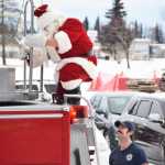 Photo by Megan Pacer/Peninsula Clarion Santa climbs down from a Kenai Fire Department engine to greet families and children gathered Friday, Nov. 25, 2016 at the Kenai Chamber of Commerce and Visitor Center in Kenai, Alaska. Some visitors lined up more than an hour before Santa arrived to take part in the annual tradition.