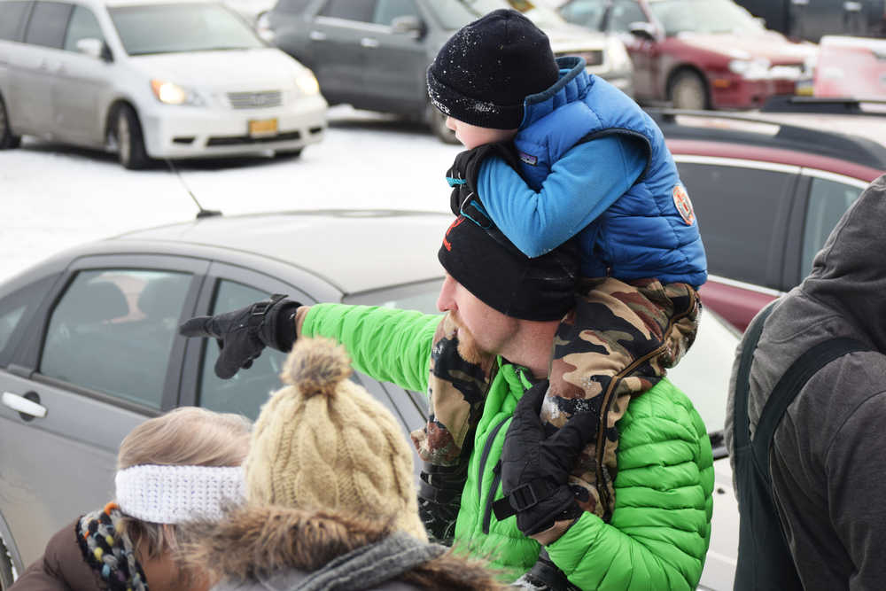 Photo by Megan Pacer/Peninsula Clarion Adam Meyers holds up his 4-year-old son, Bowe, and points in the direction Santa came from to greet families on his Kenai Fire Department engine during the annual Christmas Comes to Kenai celebration Thursday, Nov. 25, 2016 at the Kenai Chamber of Commerce and Visitor Center in Kenai, Alaska.
