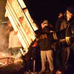 Photo by Megan Pacer/Peninsula Clarion Joe Harris tosses another pallet onto the bonfire during the annual Christmas Comes to Kenai celebration with the help of Raymond Hanson on Friday, Nov. 25, 2016 outside the Kenai Chamber of Commerce and Visitor Center in Kenai, Alaska.